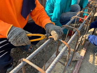 Workers are tying iron used for foundations.  In house construction