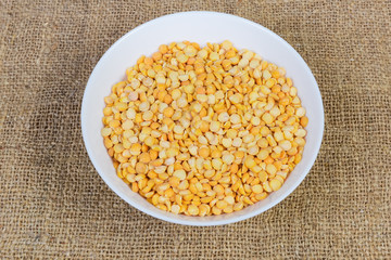 Yellow split peas in bowl on a fabric surface