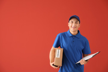 Delivery man with box and clipboard on color background