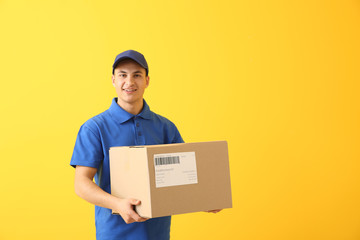 Delivery man with box on color background - obrazy, fototapety, plakaty