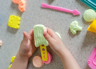 Child's hands with colorful clay.  ice cream, fruits and vegetables from plasticine.  Pastel color plasticine. Homemade clay. Close up