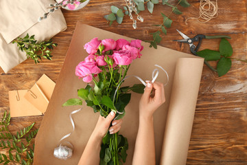 Woman making beautiful bouquet at wooden table