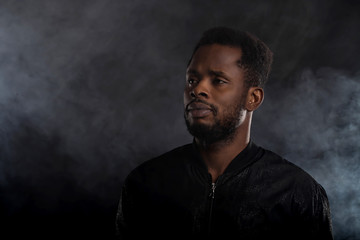 Portrait of handsome young African man on black background