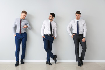 Fashionable young men near grey wall