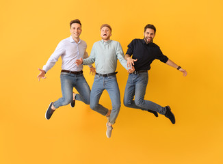Jumping young men on color background