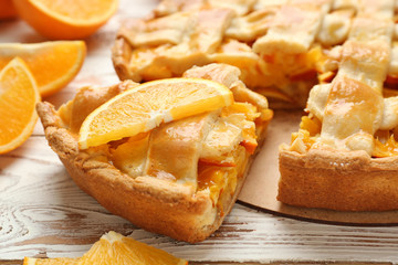 Tasty orange pie on wooden table, closeup