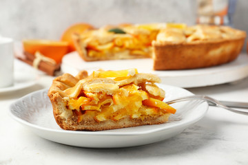 Plate with piece of tasty orange pie on table