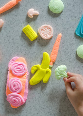 Child's hands with colorful clay.  ice cream, fruits and vegetables from plasticine.  Pastel color plasticine. Homemade clay. Close up