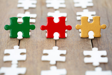 Fototapeta premium piece of Red green and gold jigsaw puzzle On the old wood And green background. teamwork concept. symbol of association and connection. business strategy.