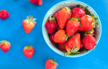 Juicy, ripe strawberries in a colorful turquoise bowl, top view