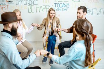 Group of diverse people keeping hands together, sitting in a circle during the psychological...