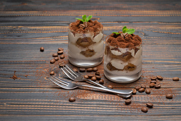 two portions Classic tiramisu dessert in a glass on wooden background