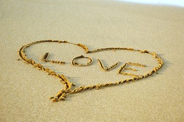 Fototapeta na wymiar Drawing heart symbol on the sand background at the beach
