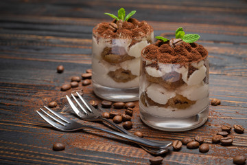 two portions Classic tiramisu dessert in a glass on wooden background