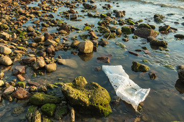 White plastic bag on the stone beach in the sunset.Thailand.