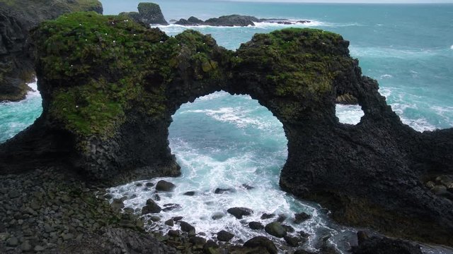 Amazing stone arch Gatklettur basalt rock on Atlantic coast of Arnarstapi in Iceland. The famous natural form arch attracts tourist to visit west of Iceland.