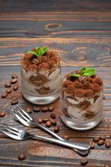 two portions Classic tiramisu dessert in a glass on wooden background
