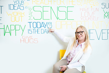 Portrait of a senior woman as a mental coach on the wall background with various inscriptions on the topic of mental health indoors