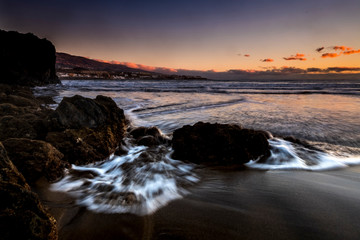 Beauty of the sea and beach in the evning dusk timeless scenic place in logn exposure - red coloured cludh beautiful sky in background - dark volcanic sand for tropical island