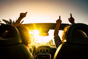 People happy for travel vacation with convertible car giving up hands and dancing for the sea...