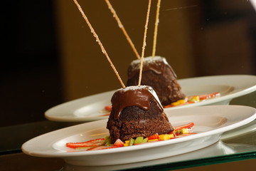 Muffin with melted chocolate accompanied by strawberries and mango.