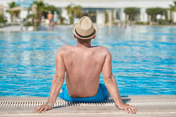 Guy in sun hat relaxing on summer vacation. Back view.