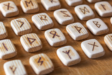 Anglo-saxon wooden handmade runes on the vintage table On each rune symbol for fortune telling is designated