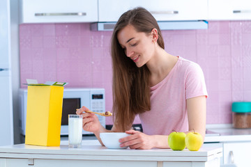 Smiling, happy attractive woman eating crispy chocolate balls for healthy cereals breakfast in morning in kitchen at home