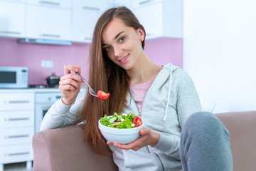 Portrait of young happy healthy woman eating vegetable salad for lunch at home. Diet and fitness eating. Clean and control food