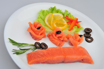 Fresh salmon decorative roses fillets, with lemon, olives on the plate. Isolated on a gray background