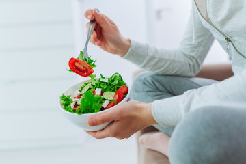 Healthy woman in sportswear holding a bowl of fresh vegetable salad. Balanced organic diet and clean fitness eating.