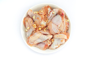 Fresh pickled chicken wings lie in a white plate. Chicken marinated with garlic, pepper and spices, on a white background.