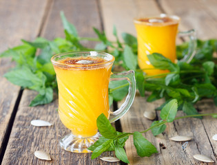 Healthy pumpkin fruit smoothie with seeds and mint leaves on table