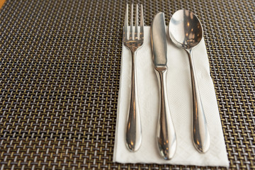 Spoon, fork, and knife on white napkin on the table.Phuket.Thailand.