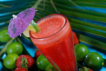 Strawberry juice with lemon served in glass and decorated with a paper umbrella.