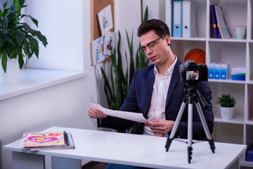 Focused dark-haired guy being concentrated on scheme on the piece of paper