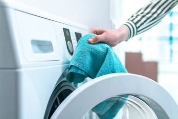 Loading towel, clothes and linen in washing machine. Doing laundry at home. Household chores and...