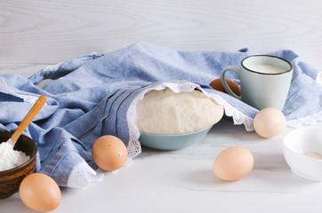 Preparing risen bread or pizza dough, flour in the bowl,eggs, cup of milk,salt.Risen dough under...