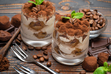 two portions Classic tiramisu dessert in a glass on wooden background