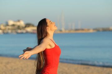Happy girl in red breathing fresh air on the beach
