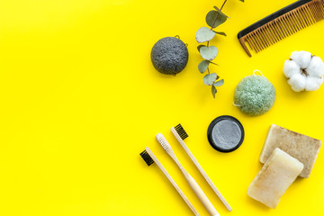 Eco materials concept with bamboo tooth brush and toothpaste with bamboo carbon on yellow background top view copy space