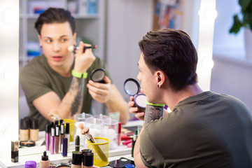 Curious handsome guy getting ready in front of mirror
