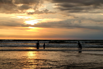 Fototapeta na wymiar tourists while enjoying the sunset on Kuta beach, with an exciting atmosphere, the color of the sky is golden and the weather is sunny, so visitors are very comfortable to linger