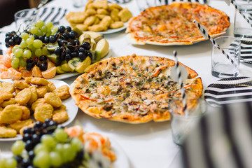 Table with pizza, fruit plate and chicken nuggets.