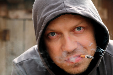 Portrait of the man in a hood with cigarette.