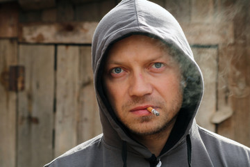 Portrait of the man in a hood with cigarette.