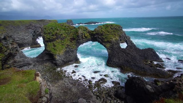 Amazing stone arch Gatklettur basalt rock on Atlantic coast of Arnarstapi in Iceland. The famous natural form arch attracts tourist to visit west of Iceland.