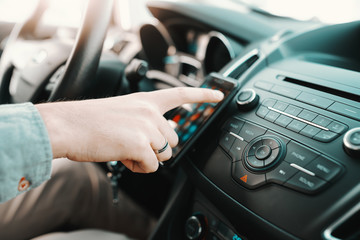 Naklejka premium Close up of Caucasian man turning on navigation on smart phone while sitting in his car.