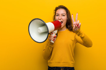 Young european woman holding a megaphone showing number two with fingers.