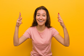 Young european woman isolated over yellow background receiving a pleasant surprise, excited and raising hands.